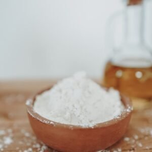 a wooden bowl filled with white powder next to a bottle of honey